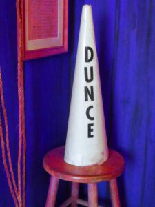 A vintage dunce cap - tall and white with dunce spelled out, in all caps, along the vertical axis.